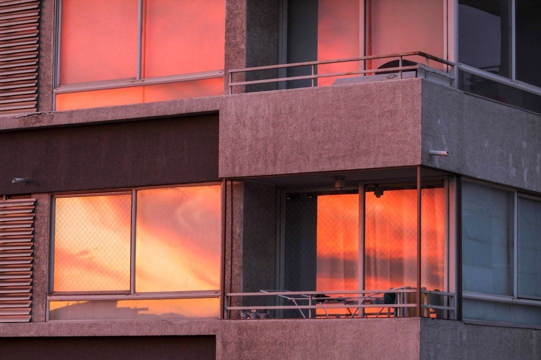 Gevel met balkons en ramen die rood-oranje avondlicht weerspiegelen